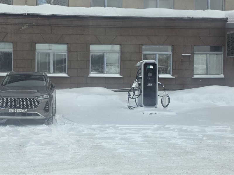 Зарядная станция Elli на площадке предприятия зимой, рядом автомобиль