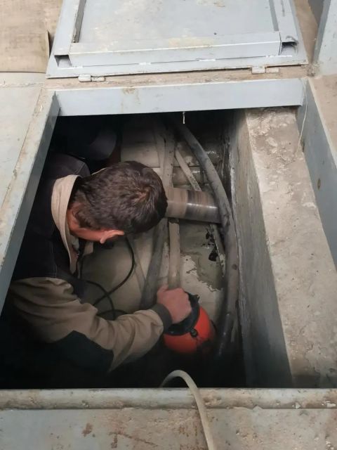 Монтажник в кабельном колодце заводит кабель питания зарядной станции